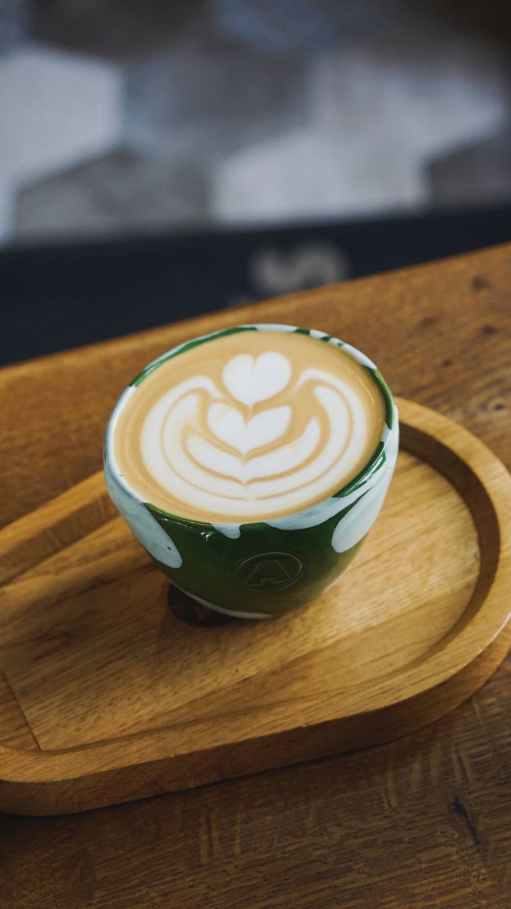 Flat white cu latte art într-o ceașcă de ceramică verde Around The Corner
